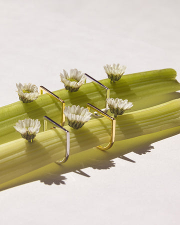 LÚDERE I Am Who I Am Rings in Silver and Gold on Celery with little white flowers
