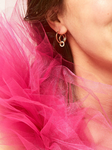 A close up of the LÚDERE Rooftop Dancing Earrings on a girl in a bright pink dress