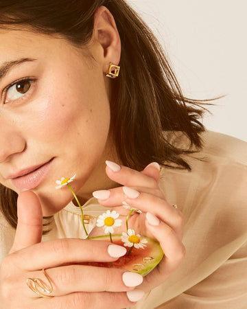 LÚDERE cube box earrings in gold vermeil on a girl holding a watermelon with white flowers in it