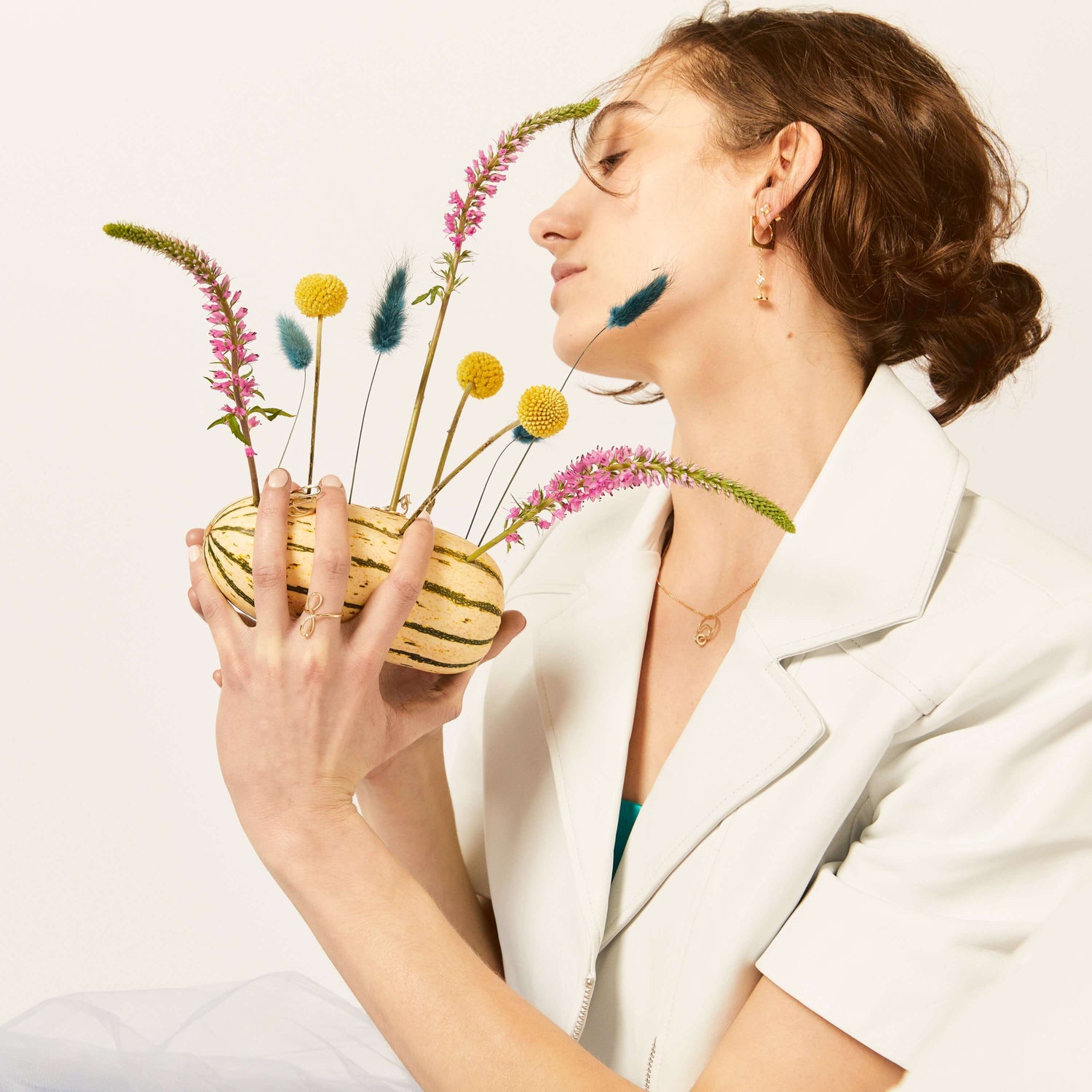 A women holding a playful arrangement of flowers modeling LÚDERE Jewelry